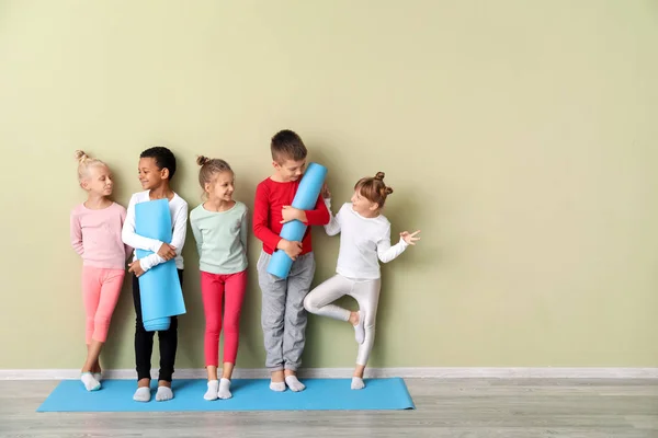 Little children with yoga mats near color wall in gym — Stock Photo, Image