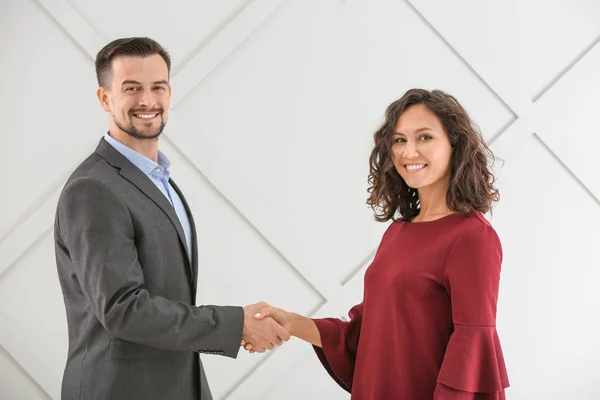 Porträt junger Geschäftsleute beim Händeschütteln vor grauem Hintergrund — Stockfoto