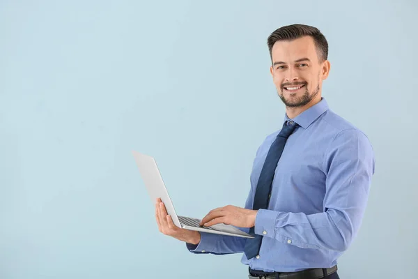 Portret van jonge zakenman met laptop op kleur achtergrond — Stockfoto