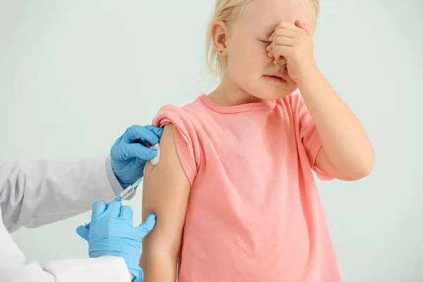 Medico vaccinare bambina su sfondo chiaro — Foto Stock