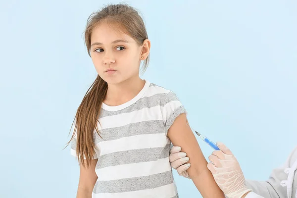 Doctor vaccinating little girl against light background — Stock Photo, Image