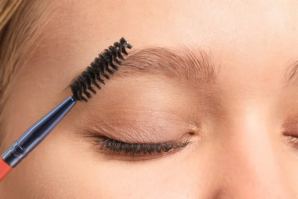 Young woman correcting shape of her eyebrows, closeup — 스톡 사진