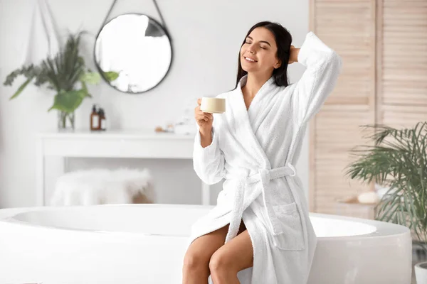 Schöne junge Frau trinkt Kaffee im Badezimmer — Stockfoto