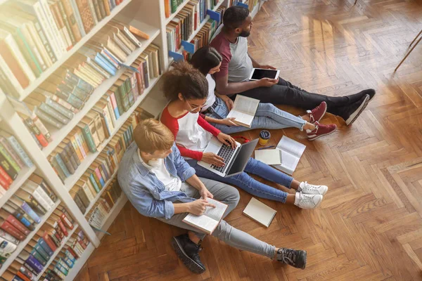 Jovens estudantes se preparando para o exame na biblioteca — Fotografia de Stock
