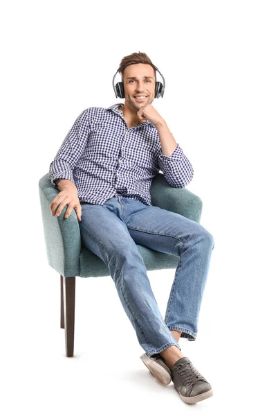 Handsome man listening to music while sitting in armchair on white background — Stock Photo, Image