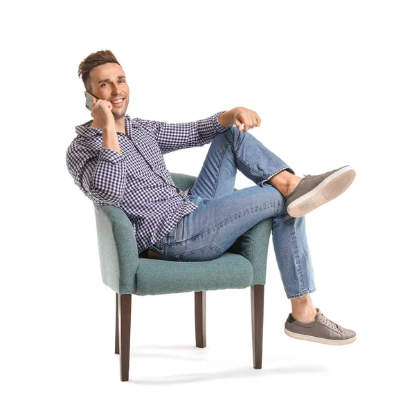 Handsome man talking by mobile phone while sitting in armchair on white background — Stock Photo, Image