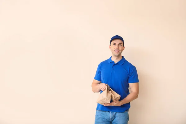 Handsome worker of food delivery service on color background — Stock Photo, Image