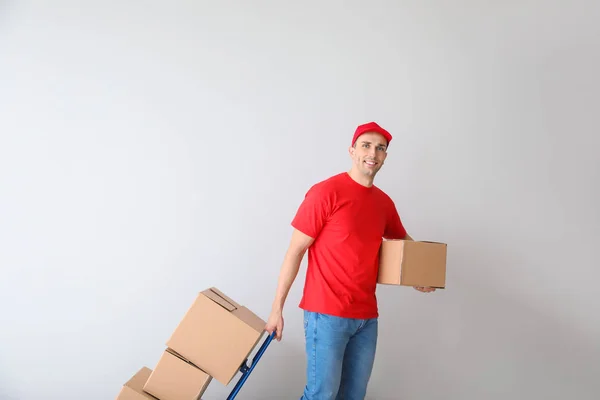 Delivery man med lådor på ljus bakgrund — Stockfoto