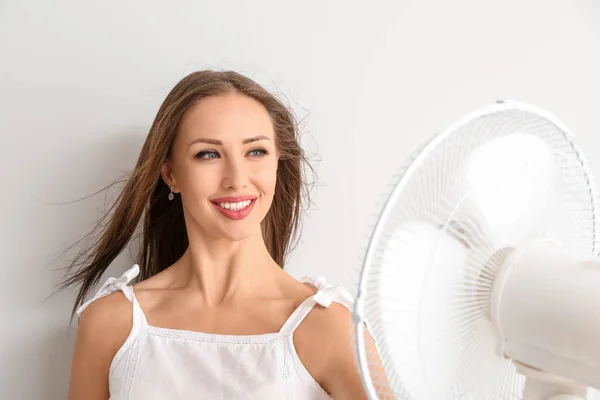 Young woman with electric fan on white background — Stock Photo, Image