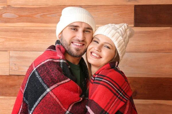 Retrato de pareja feliz envuelta en cuadros sobre fondo de madera — Foto de Stock