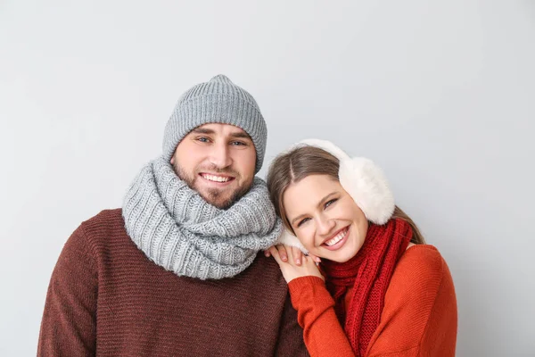 Retrato de casal feliz em roupas de inverno no fundo claro — Fotografia de Stock