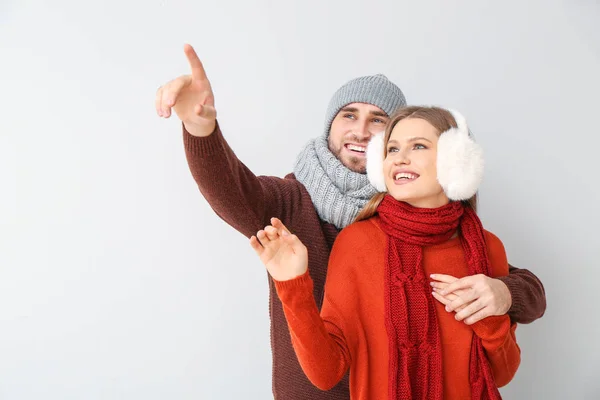 Retrato de pareja feliz en ropa de invierno mostrando algo sobre fondo claro — Foto de Stock