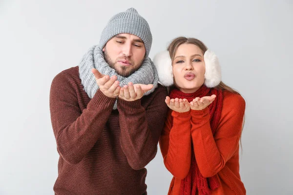 Portret van gelukkig paar in de winter kleding verzenden lucht kus op lichte achtergrond — Stockfoto