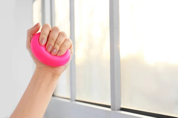 Female hand squeezing stress ball near window