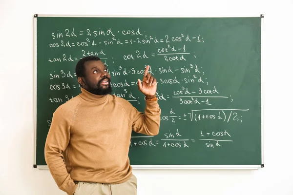 Afrikkalainen-amerikkalainen matematiikan opettaja lähellä liitutaulu luokkahuoneessa — kuvapankkivalokuva