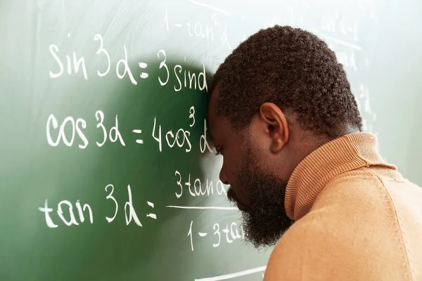 Profesor de matemáticas afroamericano desesperado cerca de la pizarra — Foto de Stock