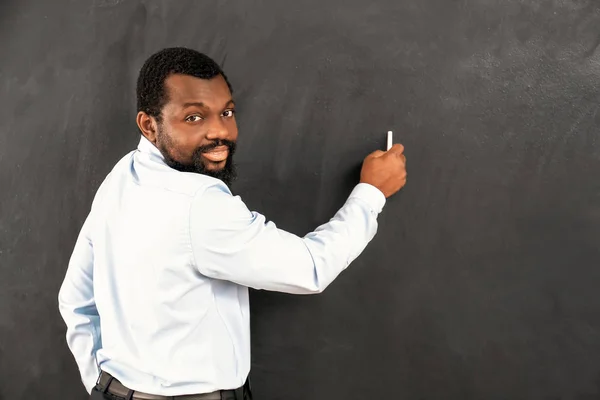 African-American teacher writing on blackboard in classroom — Stock Photo, Image