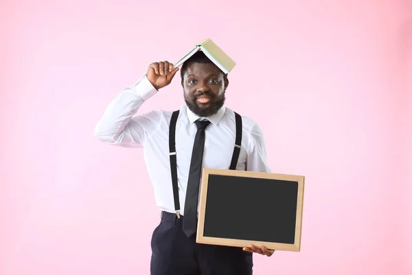 Profesor afroamericano con pizarra y libro sobre fondo de color — Foto de Stock