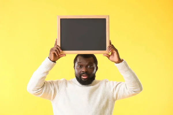 African-American teacher with chalkboard on color background — 스톡 사진