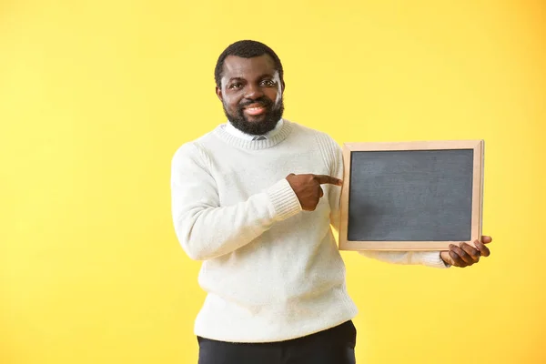 African-American teacher with chalkboard on color background — 스톡 사진