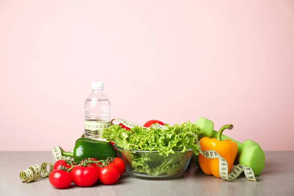 Verschillende gezonde voeding met meetlint en halters op tafel. Dieetconcept — Stockfoto