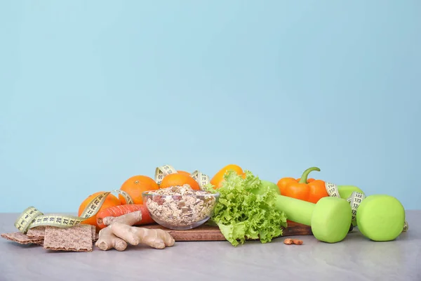 Verschillende gezonde voeding met meetlint en halters op tafel. Dieetconcept — Stockfoto