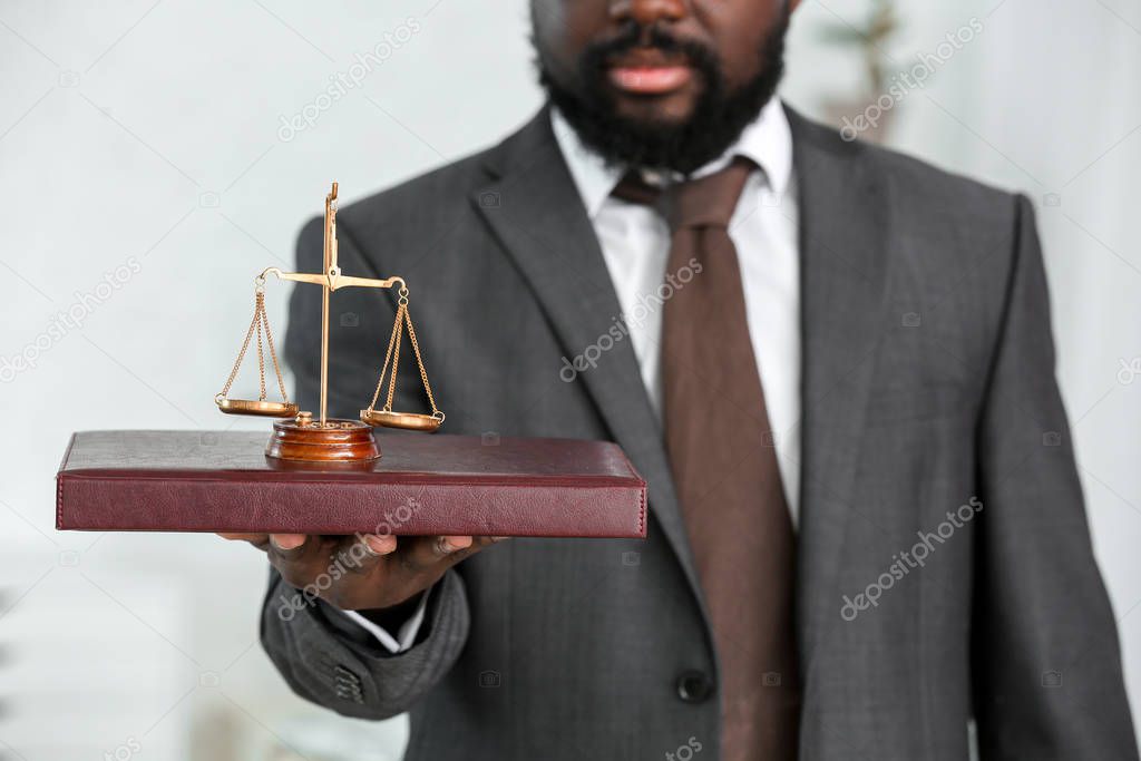 African-American lawyer with book and scales of justice in his office