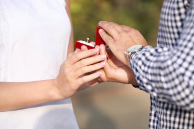 Genç adam onun sevgili için açık havada, closeup öneriyor