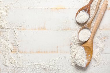 Dağınık un ve kaşıklar beyaz ahşap arka planda