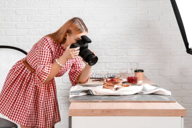 Genç bir kadın profesyonel stüdyoda krep fotoğrafı çekiyor.