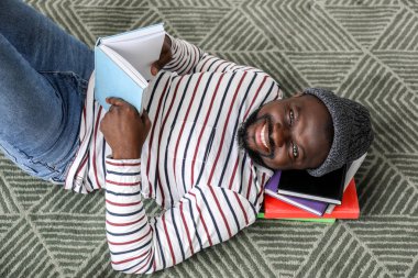 Afro-Amerikalı adam evde kitap okuyor.