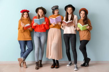 Renk duvarının yanında kitapları olan genç kadınlar