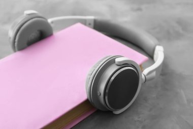 Gri arka planda kitap ve modern kulaklıklar. Ses kitapçığı kavramı
