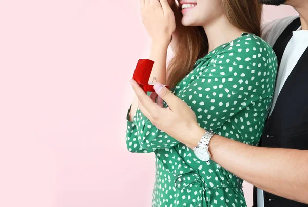 Junger Mann macht seiner Geliebten auf farbigem Hintergrund einen Heiratsantrag — Stockfoto