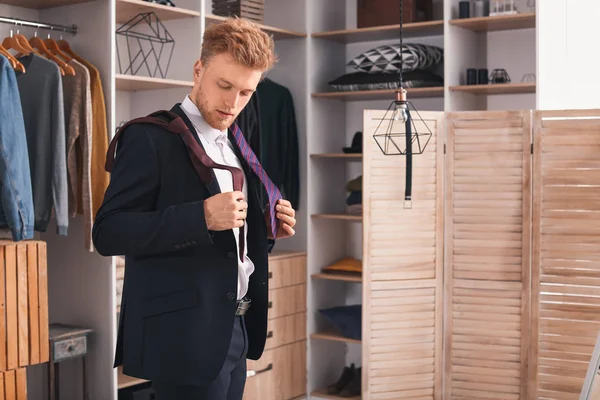 Handsome man choosing necktie in dressing room — Stock Photo, Image