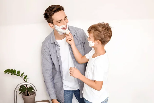 Padre con figlio che applica schiuma da barba sui loro volti in bagno — Foto Stock