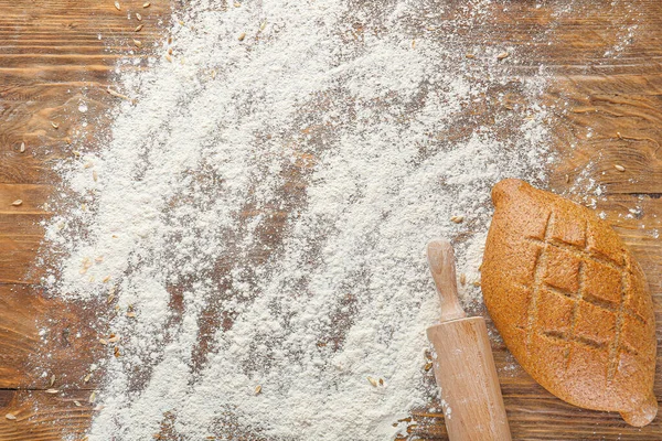 Flour, rolling pin and bread on wooden background — Stock Photo, Image