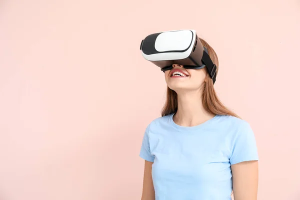 Junge Frau mit Virtual-Reality-Brille auf farbigem Hintergrund — Stockfoto