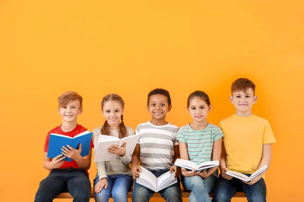 Petits enfants mignons lisant des livres sur fond de couleur — Photo