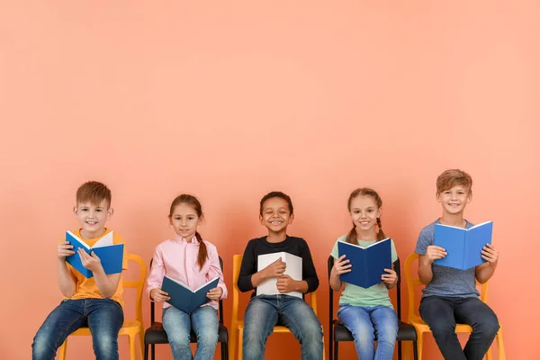 Lindos niños pequeños leyendo libros sobre fondo de color — Foto de Stock