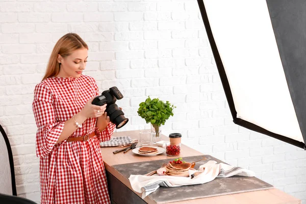 Young woman taking picture of pancakes in professional studio