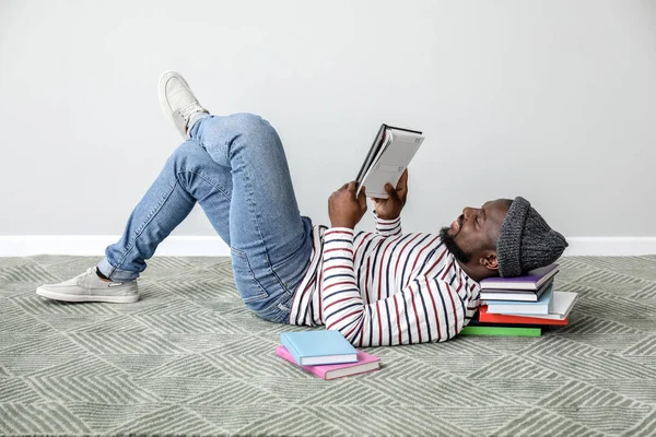 Hombre afroamericano leyendo libro cerca de la pared de luz — Foto de Stock