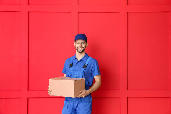 Delivery man with box on color background