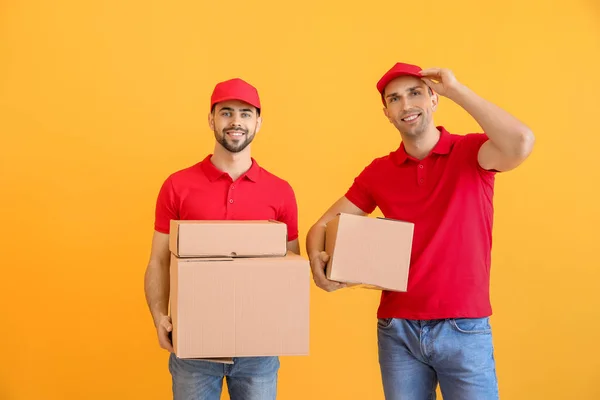 Доставка мужчин с коробками на цветном фоне — стоковое фото