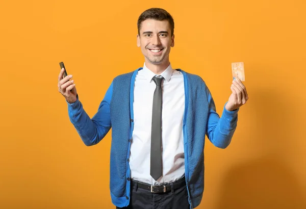 Male bank manager with credit card and mobile phone on color background — ストック写真