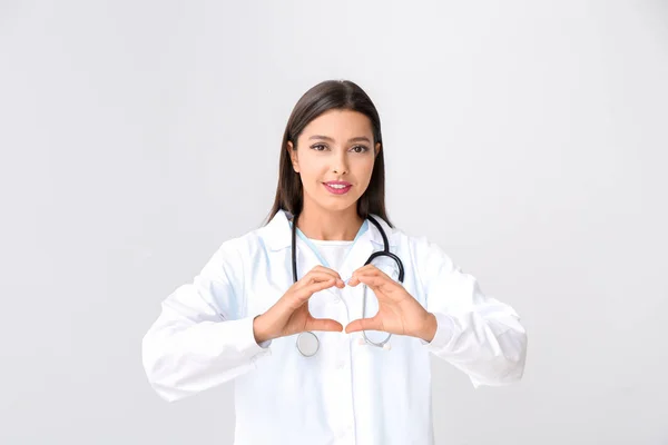 Kardiolog kobieta robi serce z rąk na jasnym tle — Zdjęcie stockowe