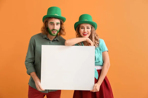 Casal jovem com cartaz em branco sobre fundo de cor. Celebração do Dia de São Patrício — Fotografia de Stock