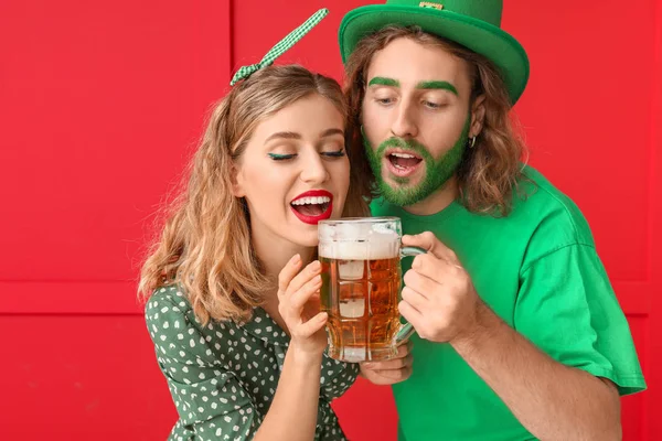 Casal jovem com cerveja no fundo da cor. Celebração do Dia de São Patrício — Fotografia de Stock