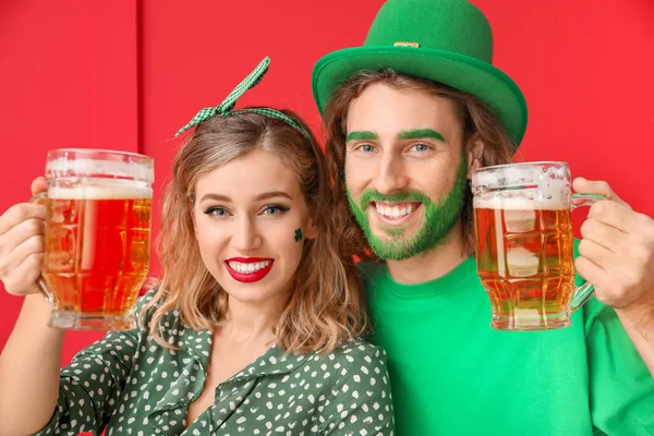 Casal jovem com cerveja no fundo da cor. Celebração do Dia de São Patrício — Fotografia de Stock