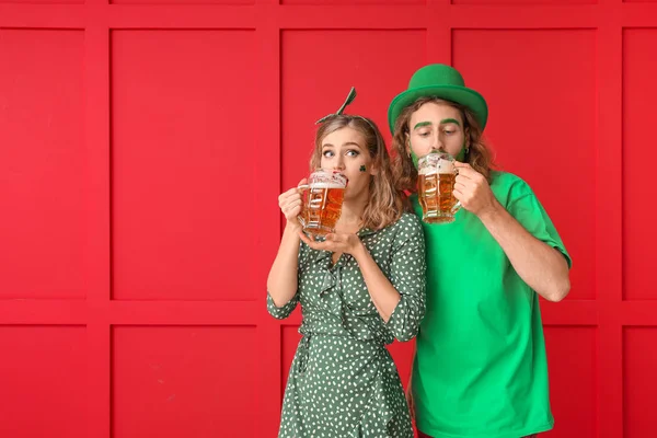 Casal jovem com cerveja no fundo da cor. Celebração do Dia de São Patrício — Fotografia de Stock